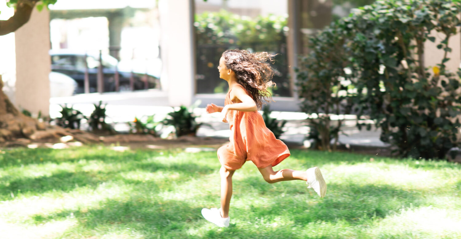 Child running on the grass with a dress on